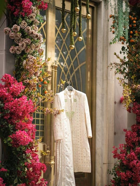Cream embroidered sherwani hanging by a golden door